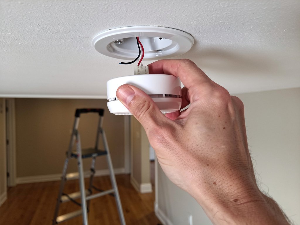 Removing a hardwired smoke detector from its mounting plate during the disconnect isolation test