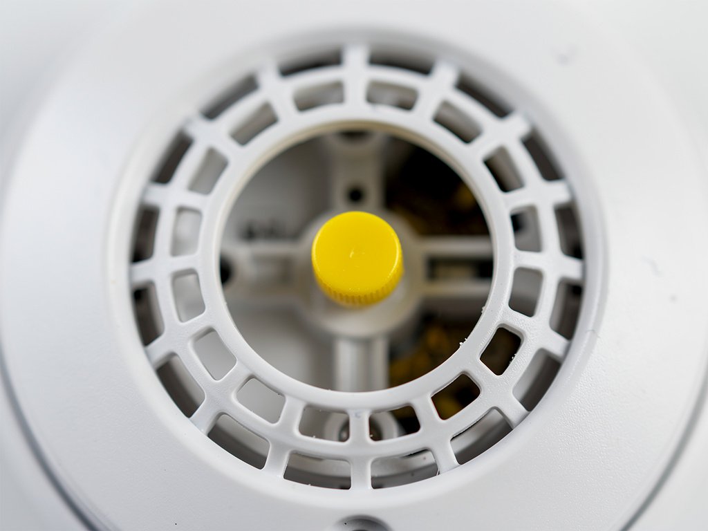 The yellow plastic cap visible through the sensor vents that indicates a recalled Kidde PI2010 or PI9010 smoke detector